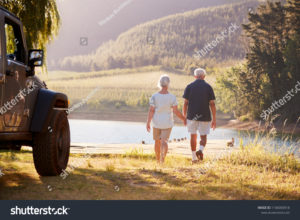 stock-photo-senior-couple-walking-by-lake-at-the-end-of-road-trip-1106000918